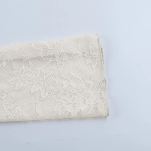 Détail du motif floral en dentelle sur un haut transparent à manches longues ivoire