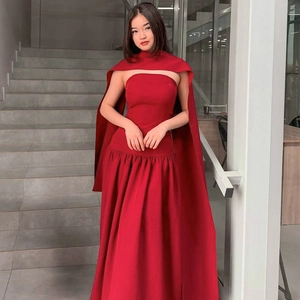 Detail of red strapless evening dress with satin shawl on elegant indoor staircase
