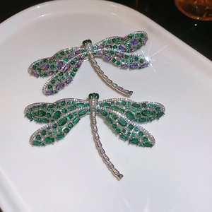Detailweergave van libelbroches met groene en paarse zirkoonstenen op zilveren metaal