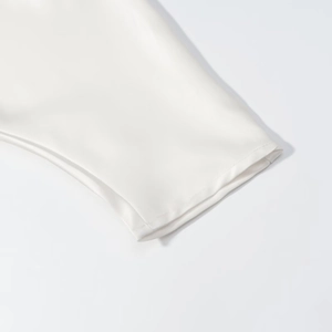 Détail de la manche d'une robe en satin blanc avec finition couture à aiguille unique
