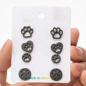 Detail of four pairs of black stainless steel cat paw and heart stud earrings on card