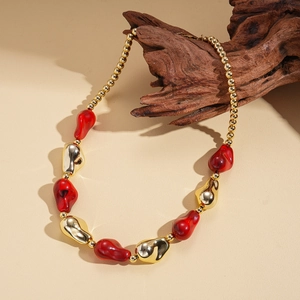 Detail of red and gold acrylic beads on wood, showcasing chunky bohemian necklace texture