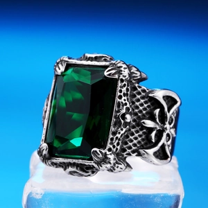 Macro detail of men's vintage steel ring with emerald-cut green stone and side carvings