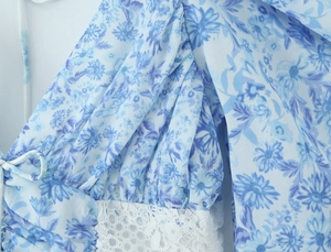 Detailed view of blue floral fabric with elegant white lace trim on the sleeve and hem
