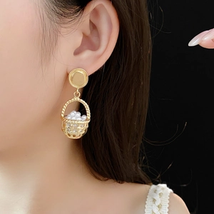 Detailed close-up of a gold-toned woven basket earring with miniature faux pearls