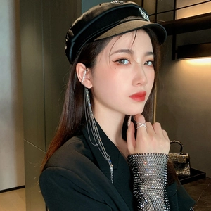 Close-up of model wearing long silver tassel earrings with pearls and a crisscross ring
