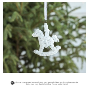 Close-up of a white glitter rocking horse ornament hanging on a green Christmas tree