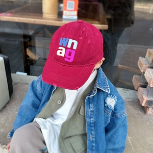 Close-up of distressed vintage red kids baseball cap with colorful letter embroidery