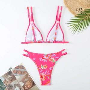 Flat lay of pink tropical floral print bikini with sun hat and vacation props