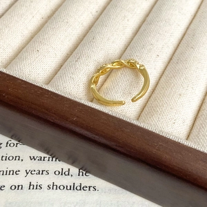 Detail of gold twisted open ring with zircon accents in a velvet jewelry box