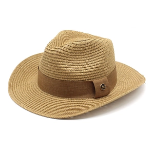 Dettaglio della trama del cappello di paglia con nastro marrone e stemma metallico M