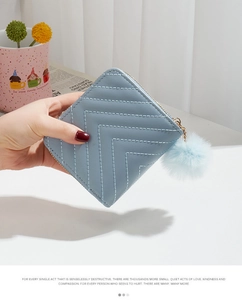 Detail of light blue PU leather wallet with V-quilted pattern and fluffy pompom keychain