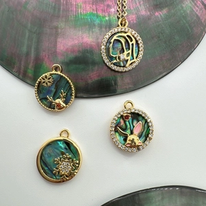 Macro detail of 18K gold plated charms with abalone shell, snowflake, reindeer and rabbit