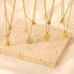 Gold layered necklaces with heart lock, disk, and star moon pendants on silk background