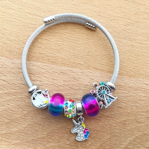 Detailed view of silver charm bracelet with unicorn and ferris wheel pendants