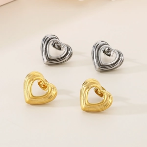 Macro shot of gold and silver hollow heart studs with unique grooved metal textures