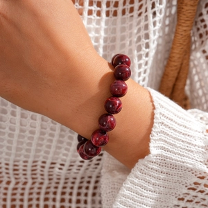 Detailed view of dark red acrylic beaded bracelet on wrist with glossy marble texture