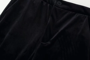 Détail du pantalon en velours noir montrant le bouton de taille et les poches