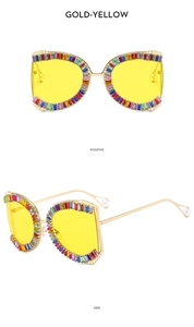 Detail of gold oversized sunglasses with multi-color rhinestones and pearl tips