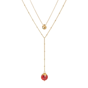 Détail d'un collier double rang doré avec pendentif irrégulier et pierre naturelle orange