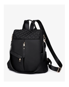 Detailed macro view of black nylon backpack featuring quilted patterns and gold metal zippers