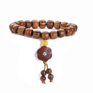 Close-up of dark rosewood Buddhist prayer beads with turquoise and flower carving