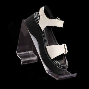 Platform sandals with white leather straps and black thick sole on display stand