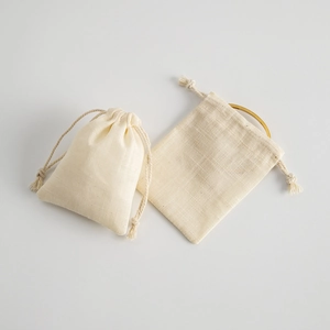 Detail of a beige drawstring cotton pouch showing texture and jewelry storage use