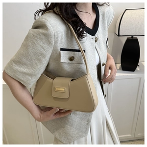 Detailed view of light beige crescent shoulder bag with golden metal buckle on model