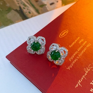 Macro shot of silver flower earrings with emerald green gemstone and zircon petals