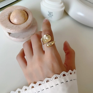 Detail of a textured gold open ring with irregular hammered finish on a female hand