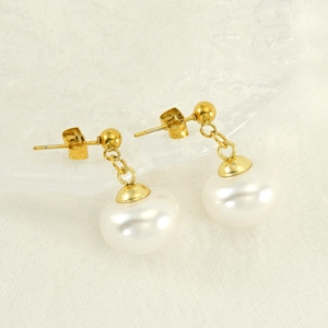 Boucles d'oreilles vintage en perles et acier inoxydable doré sur un fond en tissu élégant