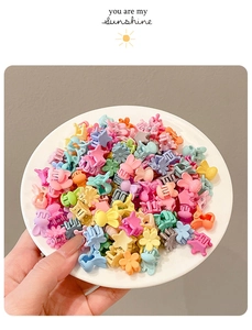Macro di mini fermagli per capelli colorati a forma di stella e fiore su piatto bianco