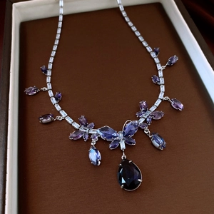 Makroaufnahme einer silbernen Amethyst-Halskette mit Schmetterlings- und Tropfenanhängern