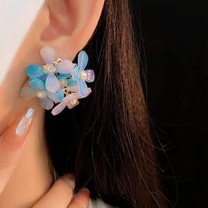 Gros plan de boucles d'oreilles fleurs dégradé bleu-violet avec perle sur modèle