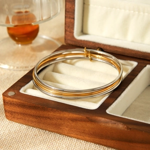 Three minimalist gold and silver stackable bangles on a velvet jewelry box lining