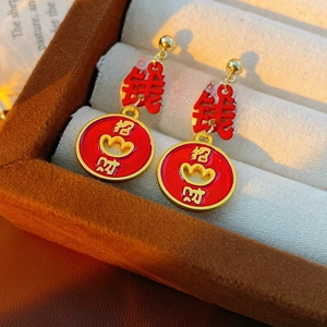 Macro shot of vintage enamel gold earrings with red tassel and fortune bag symbols