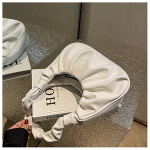 Close-up of white pleated cloud bag made of soft PU leather on a minimalist stand