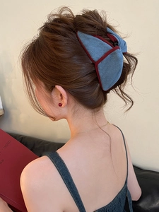 Close-up of a blue denim texture triangle hair claw clip worn on a woman's hair
