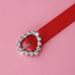 Detail of red leather belt featuring a silver heart buckle set with sparkling rhinestones