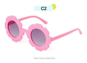 Side view of pink flower-shaped kids sunglasses with round dark lenses on white background