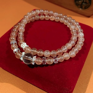 Macro shot of double-layered orange sunstone beaded bracelet with silver bow charms