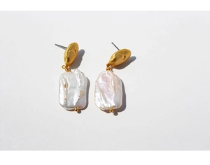 Macro detail of gold-plated baroque pearl earrings showing natural luster and texture