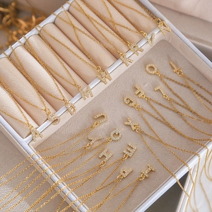 Detailed macro view of gold-plated square letter pendants encrusted with cubic zirconia