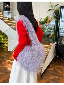 Detailed side view of the purple faux fur shoulder bag worn by a model in casual style