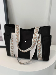 Dettaglio della borsa tote nera con spalline colorate con motivi geometrici etnici vivaci