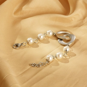 Detail of interlocking silver rings and white pearls with petal-shaped metal brackets