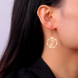 Close-up of a gold-plated stainless steel birth flower earring worn on an ear
