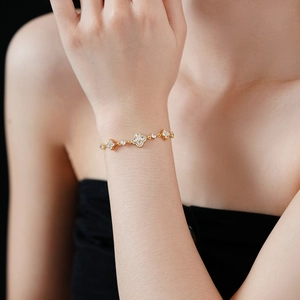 Detail of a gold-plated flower bracelet with zircon inlays on a woman's wrist