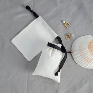 Detail of white cotton drawstring pouch with black ribbon for jewelry packaging